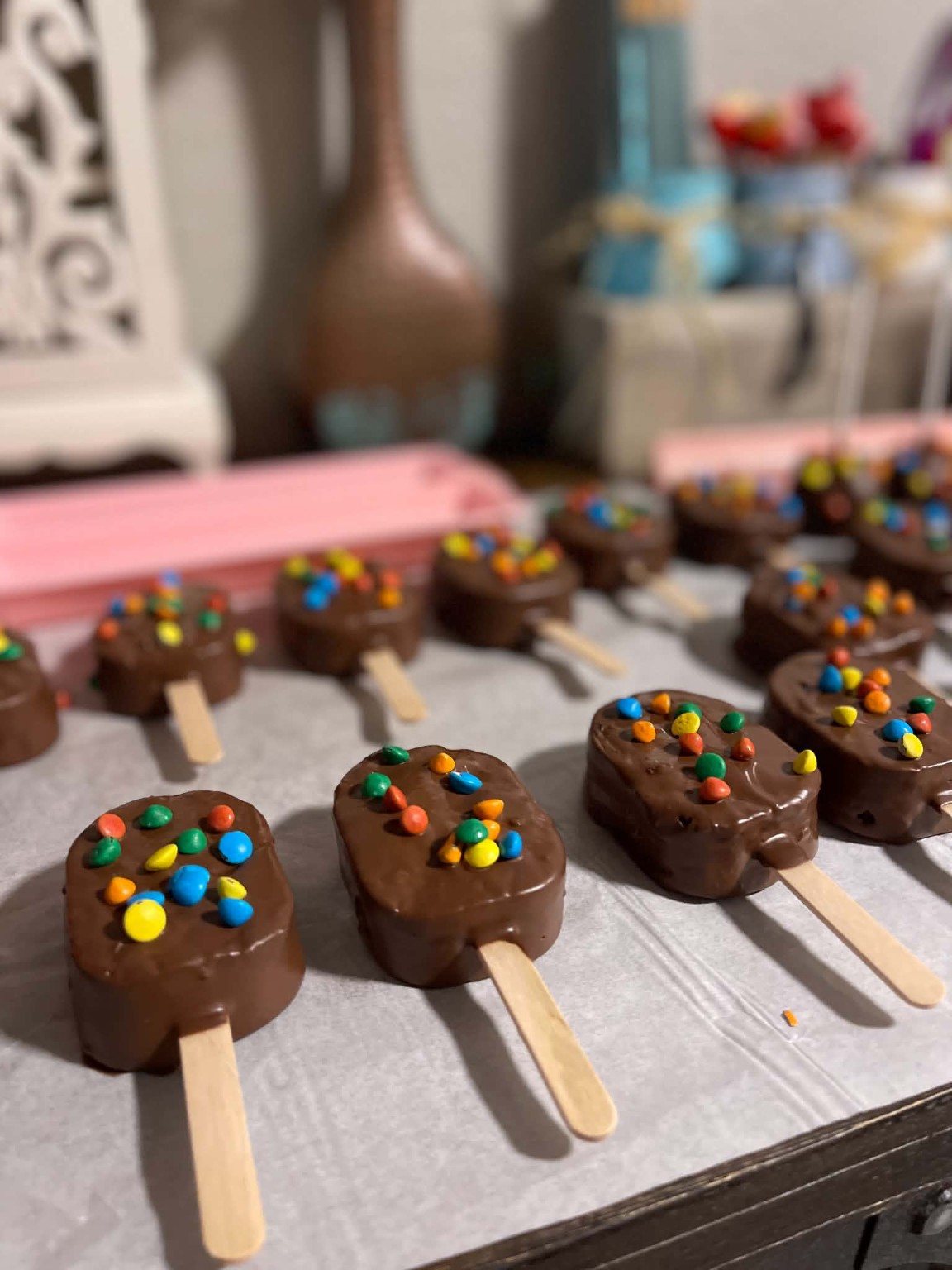 Chocolate cakesicles topped with colorful candy pieces