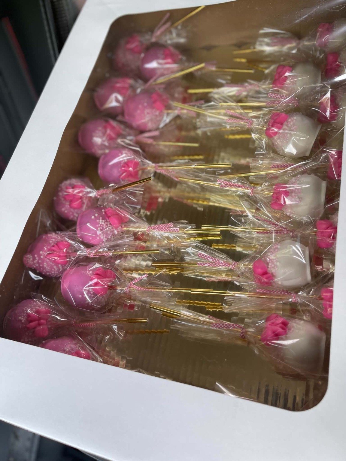 Finished pink and white bow cake pops packaged in a presentation box