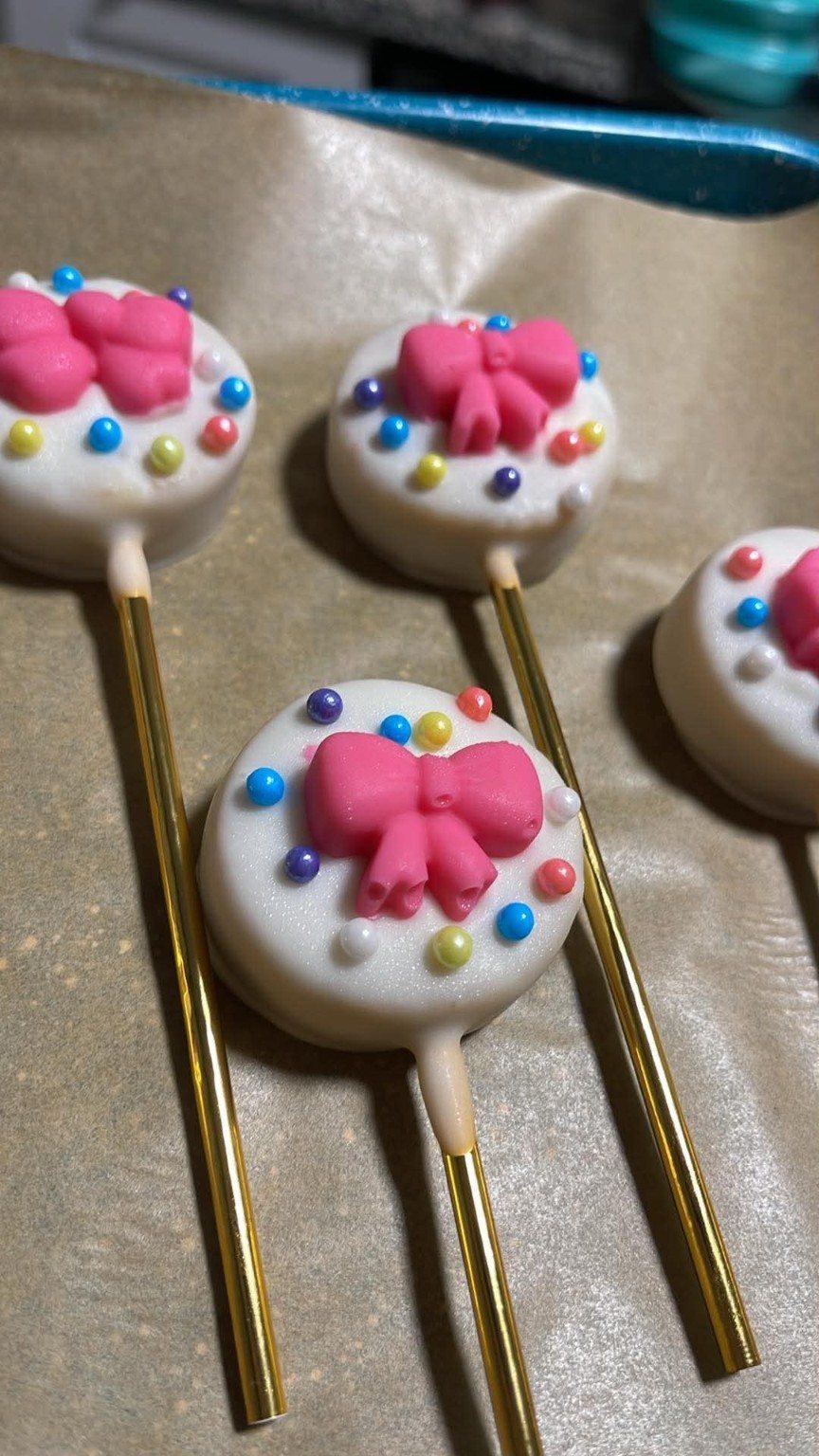 White cake pop with a pink bow and colorful pearl details